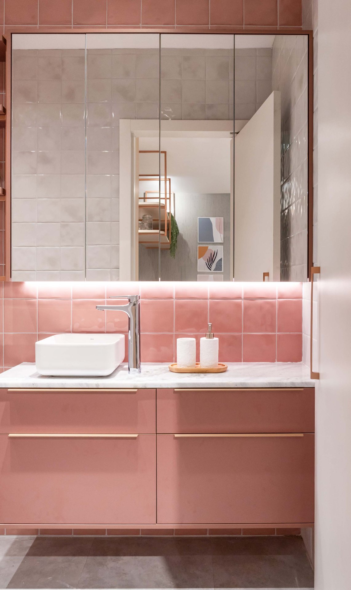 Baño con mueble suspendido en tono rosa, encimera de mármol y espejos altos