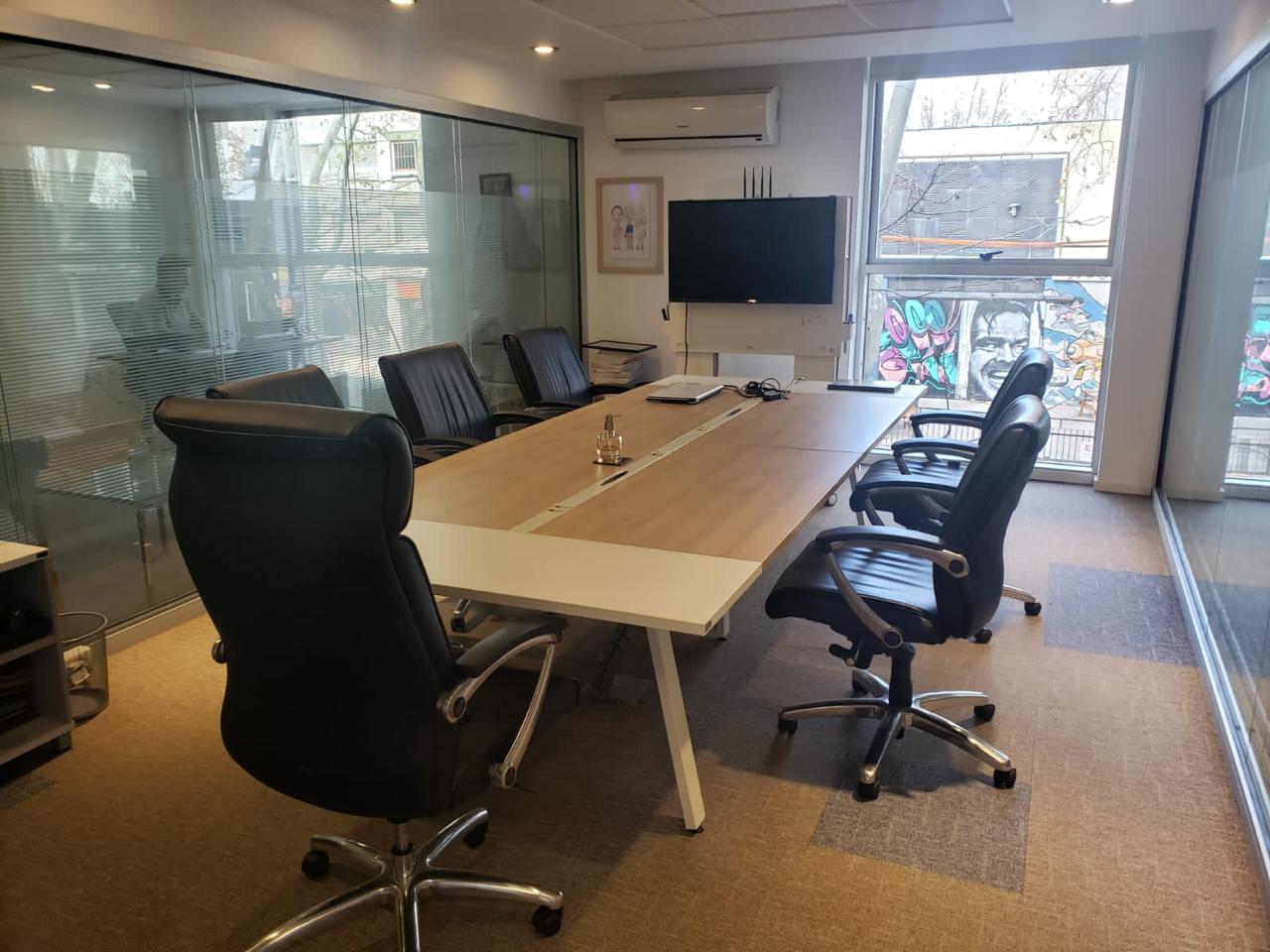 Sala de reuniones con mesa larga de madera y sillas ejecutivas