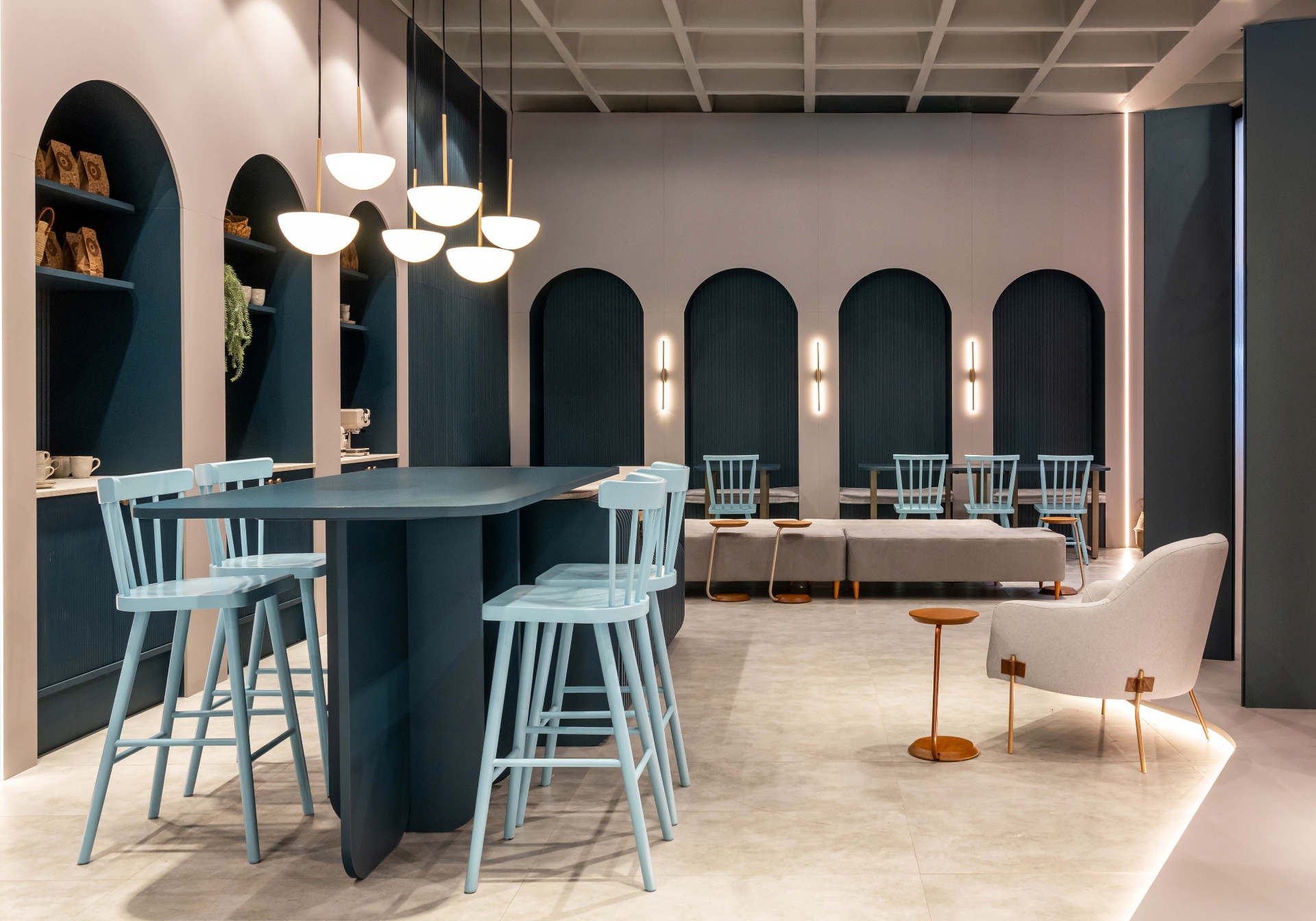 Cafetería con arcos azules, banquetas claras y luminarias suspendidas
